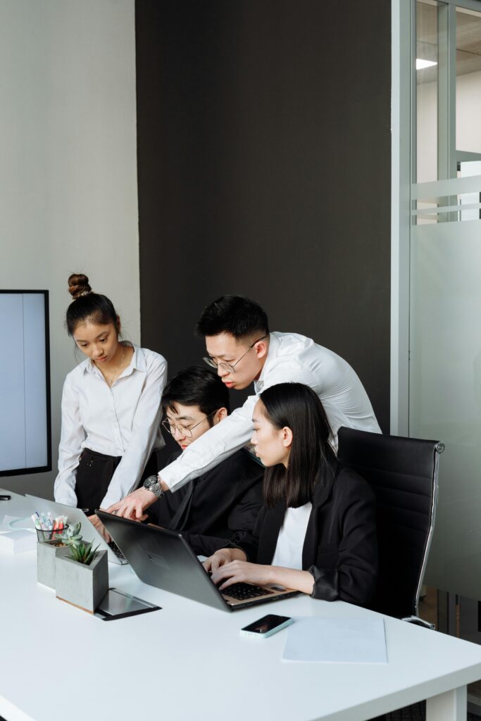 A group of professionals engaging in a business meeting with laptops in a modern office setting.