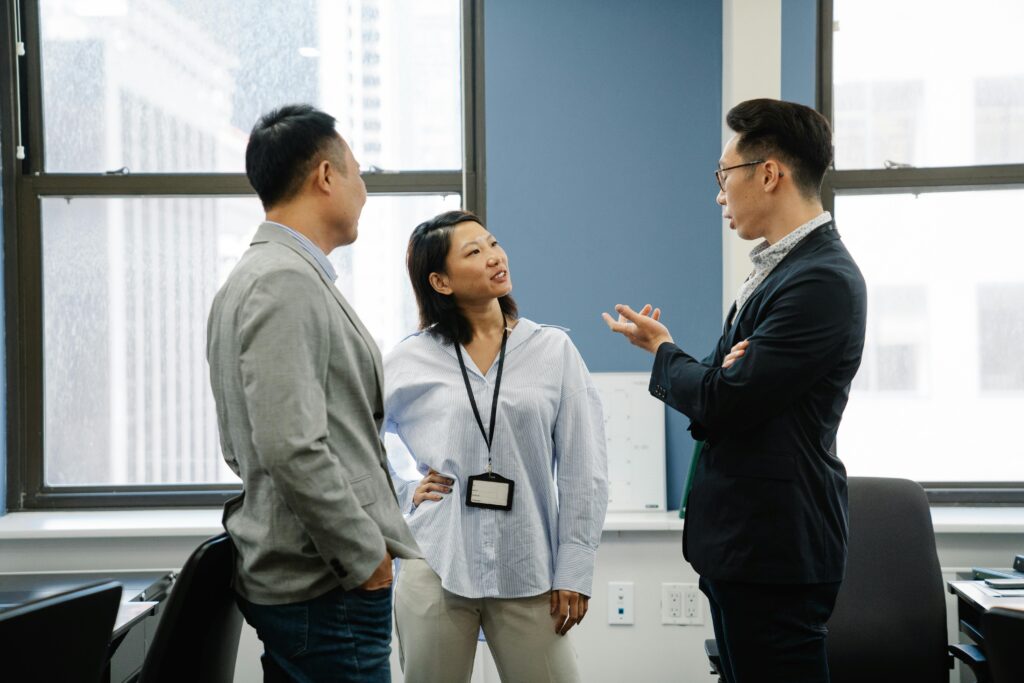 Three professional adults engaged in a lively discussion in a contemporary office environment.